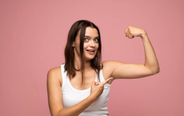 Kahverengi saçlı, yeşil gözlü, esnek kollu ve kendinden emin gülümseyen enerjik bir kadın. Beyaz atlet giyiyordu..