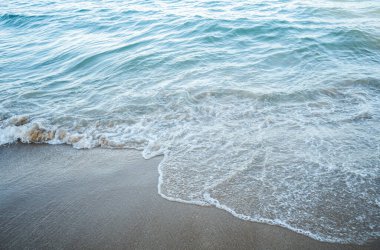 Okyanus suyuna ve köpüğe yakın, huzurlu ve doğal bir tropikal sahil manzarası yaratıyor..