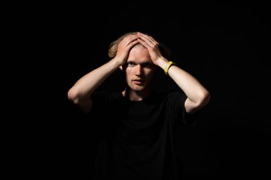 Siyah gömlekli bir adamın stüdyo portresi. İki eli de şaşkınlık ve şaşkınlık anında havada..