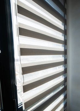 Zebra panjurlarıyla kaplı uzun, modern pencereler. Gün ışığının temiz minimalist odaya girmesini sağlayan alternatif kumaş şeritleri var..