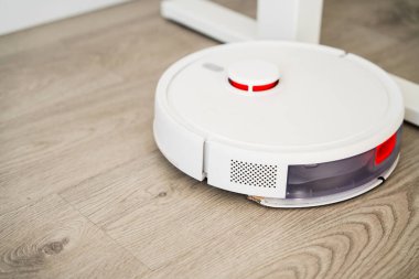 Robotik elektrik süpürgesine yakın çekim. Su tankı ahşap zemini temizler, otomatik paspas dağıtır ve modern bir iç mekan için temizlik yapar.