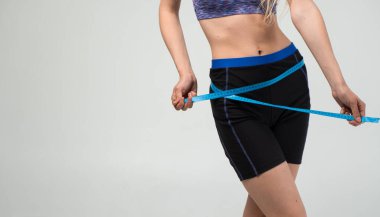 Stüdyo fotoğrafı: Siyah şortlu kadın ve mavi ölçü bandı, fitness ve vücut bakımı konseptiyle renkli üst ölçü kalçaları..