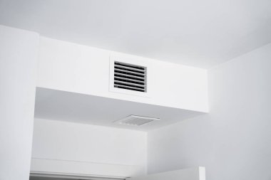 Temiz bir tavan yüzeyine kurulmuş beyaz havalandırma ızgarası hava akışı yönetimi, minimalist mimari ve işlevsel iç elementleri vurgular..