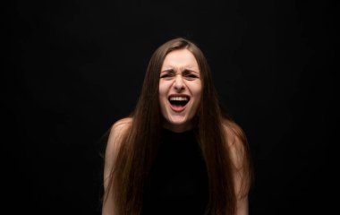 Genç bir kadın, bir stüdyo resminde, siyah bir arkaplana karşı aydınlatılmış, ham duyguları ve enerjik kişiliği hareket halinde yakalayan anlamlı bir kahkahaya daldı.