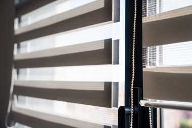 Çağdaş zebra silindirlerinin şeffaf ve opak kumaş şeritleriyle yakın çekim görüntüsü, pürüzsüz ışık kontrolü ve şık iç pencere tasarımını gösterir.