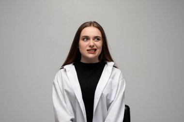 Tuhaf çarpık dişli bir yüz ifadesi gösteren genç bir kadının stüdyo portresi komik ve rahatsız edici bir yüz reaksiyonu yaratıyor..