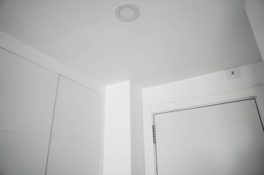 Beyaz duvarlar, tavan çizgileri ve modern minimal kapı tasarımı içeren iç mimarinin soyut görüntüsü.