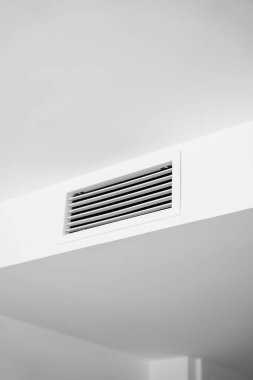 Modern bir apartmanın beyaz tavan tasarımına entegre edilmiş dikdörtgen havalandırma ızgarası..