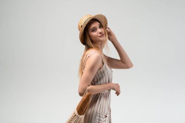 Yazlık kıyafetle poz verirken, yeniden kullanılabilir bir alışveriş poşeti ve ekmek tutan kadın model. Eko yaşam tarzı kavramı, plastik ücretsiz alışveriş, yavaş yaşam ve doğal kadınlık..