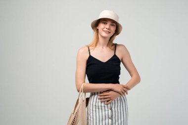 Elinde taze meyve, sebze ve ekmek, sürdürülebilir alışveriş ve eko yaşam tarzı konseptiyle yeniden kullanılabilir ağ çantası tutan gülümseyen genç kadın.