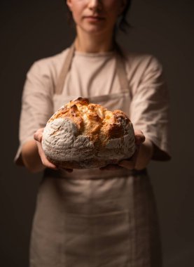 Kırsal un tozlu ekmek somunu sunan dişi fırıncı. Ekşi ekmek pişirme, geleneksel yöntemler, organik malzemeler ve zanaatkar fırın kavramı