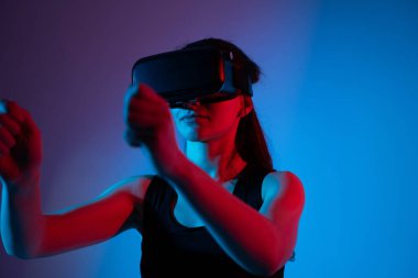 Sanal gerçeklik kulaklığı kullanan ve el hareketi yapan bir kadın. Sezgisel etkileşim kavramı, hareket yönlendirmesi, dijital deneyim ve geleceksel arayüz.