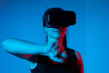 Kadın sanal bir çevreyle iletişim kurmak için öne uzanıp bir nesne seçiyor. Uzaysal etkileşim kavramı, hareket kontrolü, büyüleyici teknoloji ve dijital deneyim..