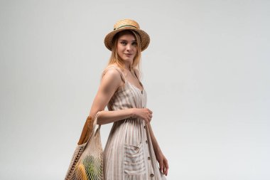 Tekrar kullanılabilen bir poşet dolusu yiyecek taşıyan bir kadın. Sıfır atık alışverişi, çevre dostu alışkanlıklar, organik gıda, sürdürülebilir yaşam tarzı ve gevşek yaz havası kavramı.