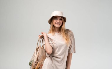 Sebze ve ekmek dolu bir alışveriş çantasıyla ayakta duran genç bir kadın. Asgari sürdürülebilir yaşam tarzı, çevre dostu alışveriş ve sağlıklı gıda tüketimi kavramı.