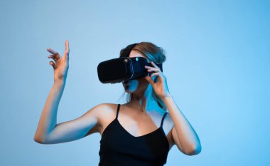 VR kulaklık takan kadın sanal ortamda elini hareket ettiriyor. Kapsamlı teknoloji kavramı, simülasyon, dijital etkileşim ve yenilikçi kullanıcı deneyimi.
