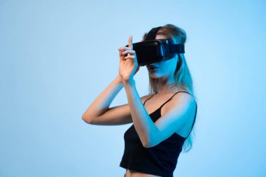 Sanal gerçeklik kulaklığı takan ve ayarlayan genç bir kadının yan görüntüsü. Kapsamlı teknoloji kavramı, dijital etkileşim, yenilik ve gelecekteki deneyim.