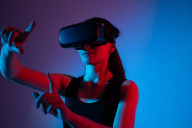 VR kulaklık takan kadın kullanıcı, sanal bir arayüzle etkileşim kurmak için çimdik ve işaret el hareketleri kullanıyor. Jest temelli kontrol kavramı, büyüleyici teknoloji ve dijital navigasyon.