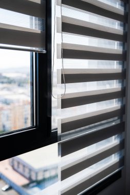 Dikey bileşim zebra panjurlarını ve zincir kontrol mekanizmasını vurguluyor, modern bir iç mekanda gün ışığında ışık yayılımı, doku ve işlevselliği vurguluyor.