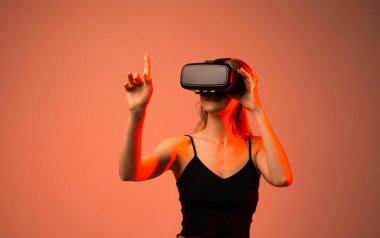 Kadın kullanıcı sanal gerçekliği VR kulaklık ve el hareketleriyle keşfediyor. Gelecekçi teknoloji kavramı engin deneyim, yenilik, dijital etkileşim ve modern eğlence göstermektedir..