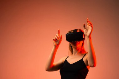 Genç bir kadın dijital çevreyi iki eliyle kontrol ederken sanal gerçeklik oyunlarından zevk alıyor. VR oyunları, etkileşimli eğlence, yenilik ve gelecek teknolojisi kavramı.