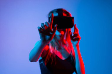 Sanal gerçeklik gözlüğü takan kadın kullanıcı, el hareketleriyle dijital arayüzle etkileşime girer, metaevren navigasyonunu, yenilikçiliği ve büyüleyici teknolojiyi temsil eder..