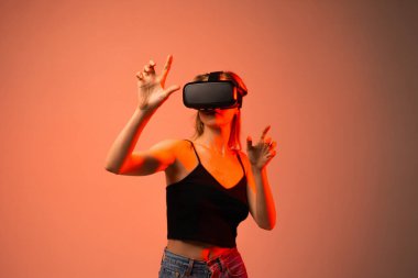 Genç bir kadın sanal bir arayüzle iletişim kurarken VR kulaklık takıyor. Metaevren kavramı, dolambaçlı teknoloji, yenilik ve gelecekteki dijital deneyimler.