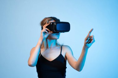 Yaratıcı kadın sanal gerçeklik ortamında çalışırken el hareketlerini kullanır. VR tasarım kavramı, dijital arayüz oluşturma, etkileşimli ortam, kullanıcı deneyimi tasarımı ve yenilikçi yaratıcı teknoloji.