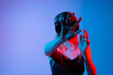 VR kulaklık takan kadın, görsel gerçeklik, insan-bilgisayar etkileşimi ve gelecekteki teknoloji kavramlarını gösteren görünmez bir dijital arayüze uzanıyor..