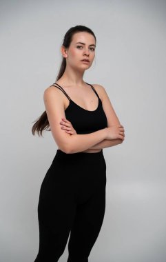 Stüdyoda kolları çapraz duran sağlıklı bir kadın azim, disiplin, vücut güveni ve odaklanmış modern sağlıklı yaşam tarzı kavramını ifade ediyor..