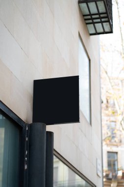 Modern bir bina duvarından yansıyan boş siyah kare işareti, bir marka logosu veya şehir vitrininde reklam mesajı göstermek için ideal bir model oluşturur