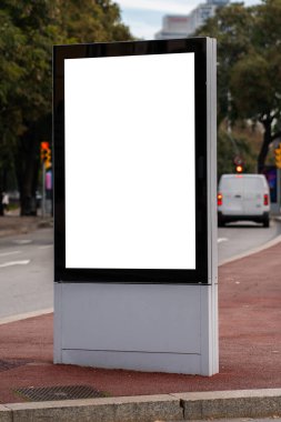 Reklam, pazarlama veya şehir caddesinde trafik ve ağaçların bulanık arkaplanda olduğu bir sokakta temiz beyaz dikey kopyalama alanı sunan boş reklam panosu modeli
