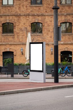 Boş bir sokak reklam panosu ve kaldırımda fotokopi alanı sağlayan reklam afişi. Şehir ortamında pazarlama için boş bir açık dijital ekran gösteriliyor