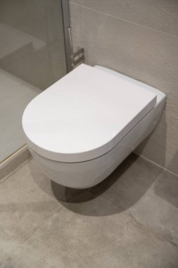 Modern duvar askılı tuvalet, temiz beyaz bir estetik ve zarif bir minimalist tasarım içeriyor, banyo hijyenini arttırıyor ve çağdaş iç mekanlarda yer kaplıyor.