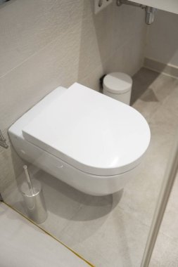 Minimalist modern bir banyoda beyaz kapalı klozet, temiz seramik fikstür hijyeni yansıtıyor, çağdaş ev tasarımı ve derli toplu, fonksiyonel iç dekorasyon ve mimari