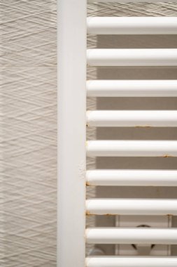 Beyaz boyanmış banyo havlusu demiryolu kaloriferi metal çubuklarındaki paslanma ve aşınma lekeleriyle bozuluyor. Ev tesisat sistemlerinde yaygın bir yıpranma ve yıpranma sorununa işaret ediyor.