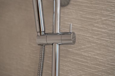 Modern krom duş donanımı dokulu bir duvara monte edilir, ışığı yansıtır ve çağdaş bir banyo ve kişisel bakım için parlak, temiz bir tasarım sunar.