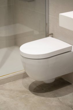Çağdaş bir banyoda kapalı kapaklı duvara monte edilmiş tuvalet, temiz bir tasarım için modern hijyen donanımı kuruluyor, hijyen konforu ve iç dekorasyona odaklanıyor