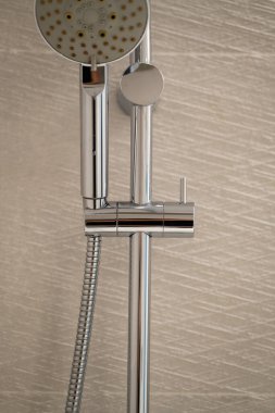 Ana duş başlığı ve esnek hortumu modern bir banyo duvarına monte ederek vücut bakımı ve günlük hijyen ritüelleri için temiz bir ortam yaratıyor.