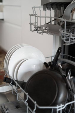 Modern bir mutfakta temiz tabak, tabak ve çatal bıçak dolu bulaşık rafı, düzenli, verimli bulaşık yıkama ve günlük ev işleri kolaylığı ve hijyen