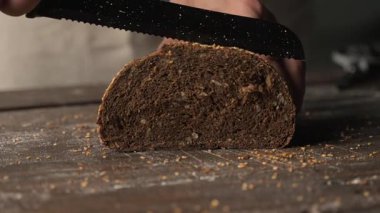 Fırıncılar ustaca fırınlanmış taze, sağlıklı bir çavdar ekmeğini tırtıklı bıçakla dilimleyen eller. Sağlıklı, besleyici ev yapımı mutfak fikrini vurguluyorum.