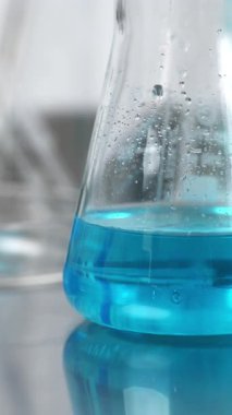 Cam Erlenmeyer şişesi, içinde mavi sıvı çözelti bulunan bir bilim laboratuarı. Tıbbi araştırma ve kimyasal geliştirme kavramları