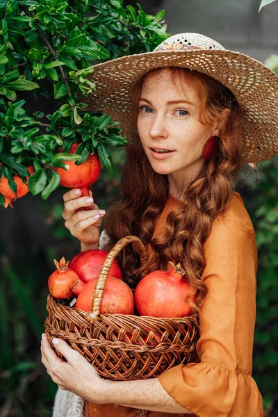 주황색 드레스입은 모자쓴 여자와 열매를 아름다운 정원에 — 스톡 사진