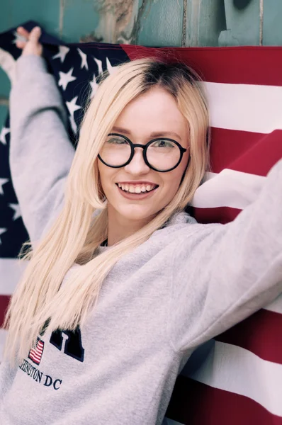 Retrato ensolarado de uma menina loira com bandeira americana em sua mão — Fotografia de Stock