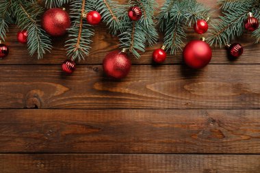 Ahşap Noel arkaplanı, kırmızı süslemeler ve köknar ağacı dalları. Noel bayramı kutlaması, kış, yeni yıl konsepti. Noel afişi modeli, tebrik kartı şablonu