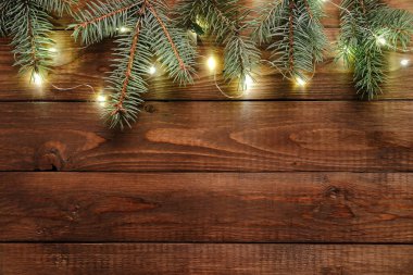 Noel ışıkları ampulü ve çam ağacı dalları eski ahşap masa süslemeleri. Mutlu Noeller ve yeni yıl tatili geçmişi. Düz yatış, üst görünüm.