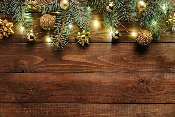 Wooden Christmas background with golden decorations, baubles, fir tree branches, garland. Christmas holiday celebration, winter, New Year concept. Christmas banner mockup, greeting card template