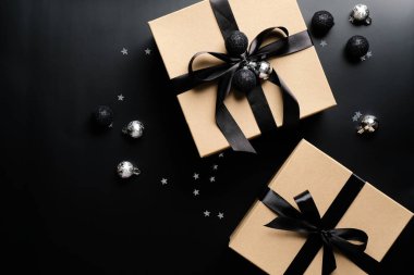 Zarif Noel hediyeleri ve siyah arka planda toplar. Düz yerde, üst tarafta. Noel sürprizi, yeni yıl hediye kutusu konsepti.