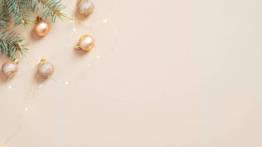 Noel ağacı dalları, toplar ve pastel bej arka planda altın çelenkler. Hygge, rahat, İskandinav Noel kompozisyonu. Asgari düzeyde. Düz yatış, üst görünüm.