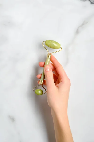 Mão Feminina Segurando Jade Pedra Rolo Facial Sobre Mesa Mármore — Fotografia de Stock